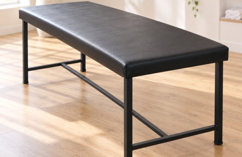Mild steel treatment table with a black padded top and cross braced base